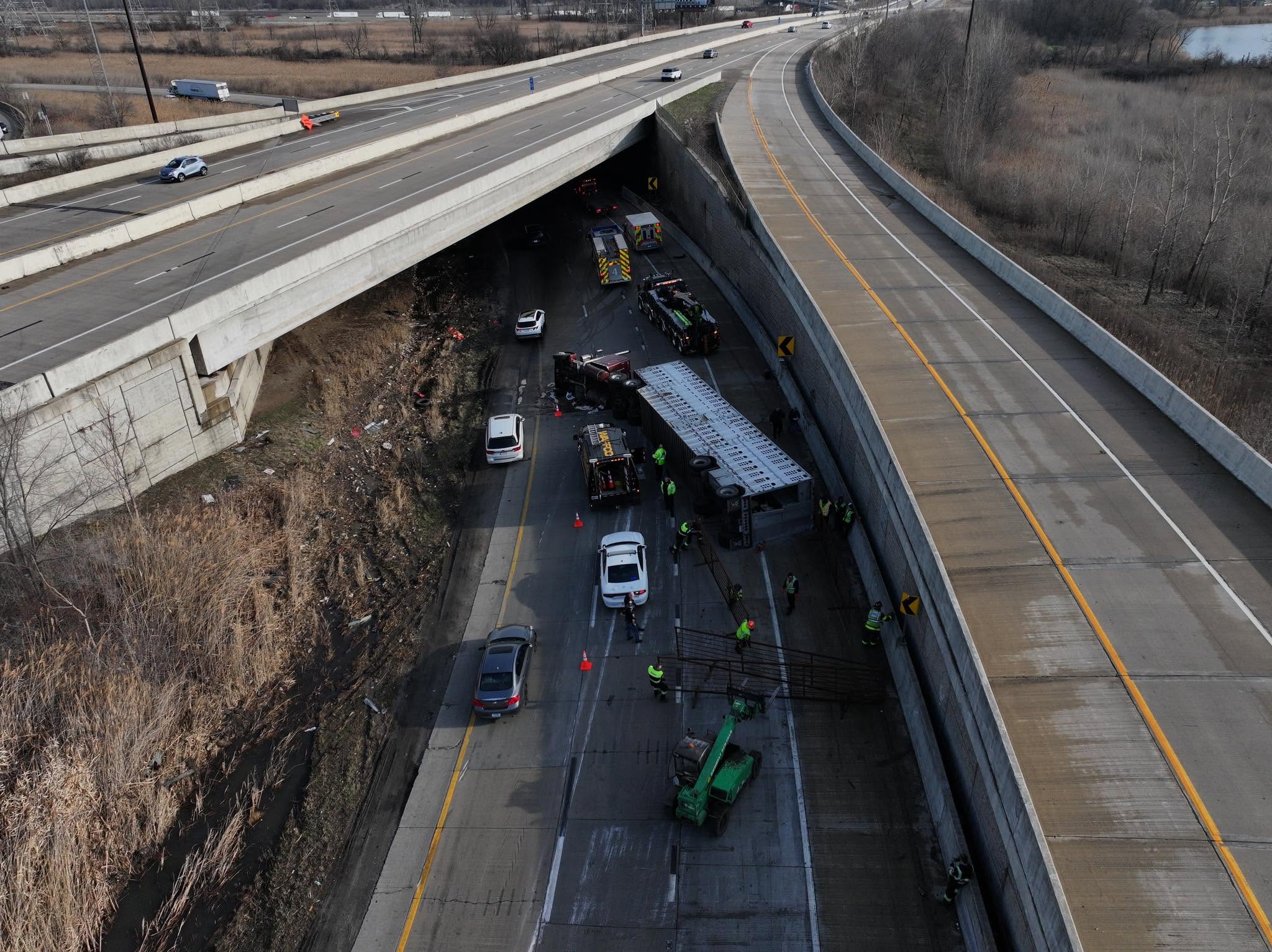 Crews working an overturned commercial vehicle under an overpass