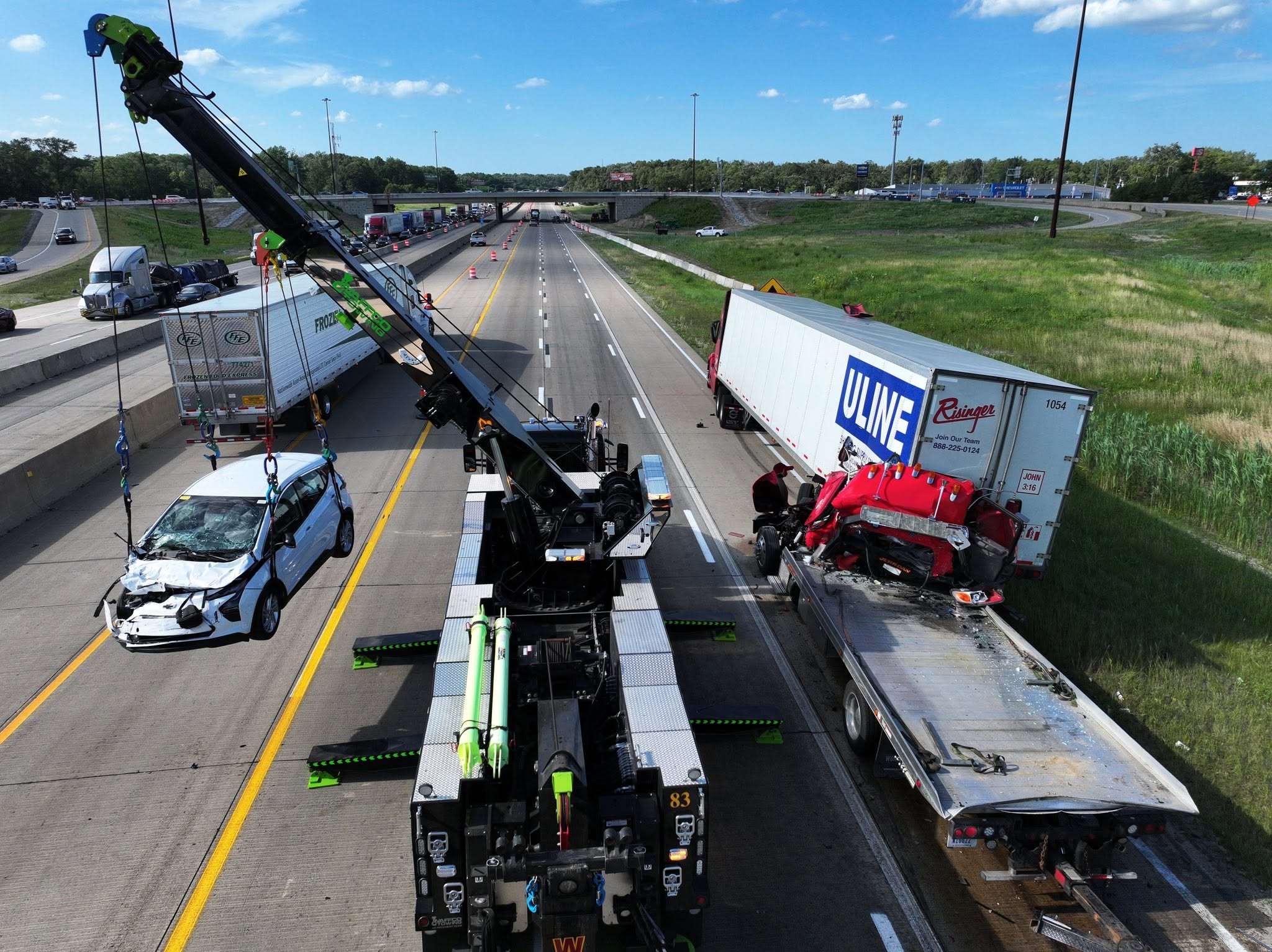 Rotator lifting a damaged vehicle near tractor trailers