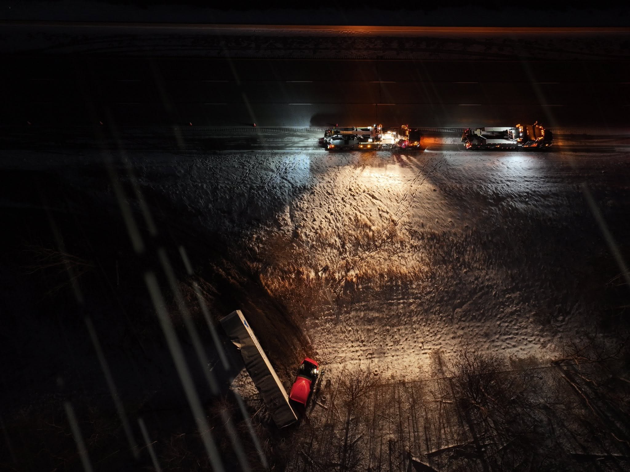 Aerial night view of recovery trucks lighting an off-road scene