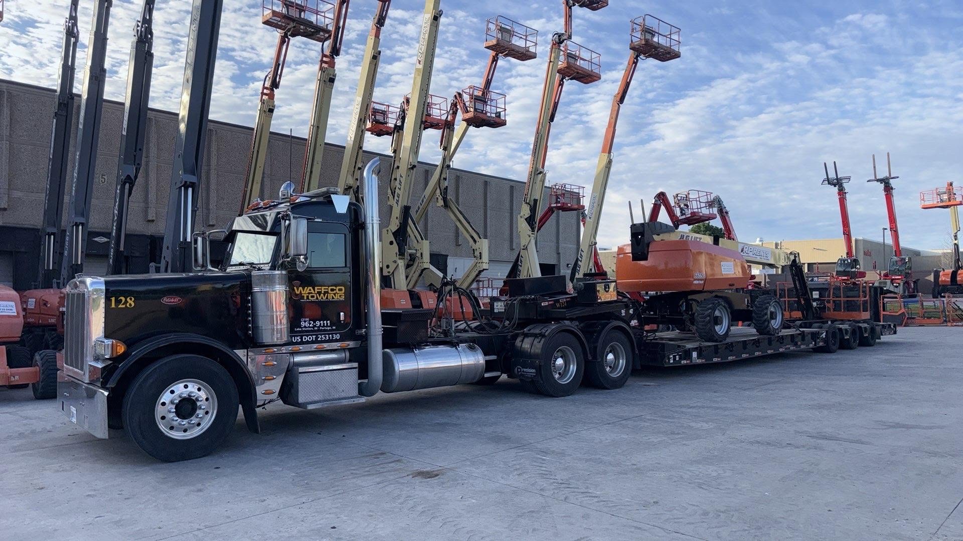 Waffco power unit hauling boom lifts on a trailer