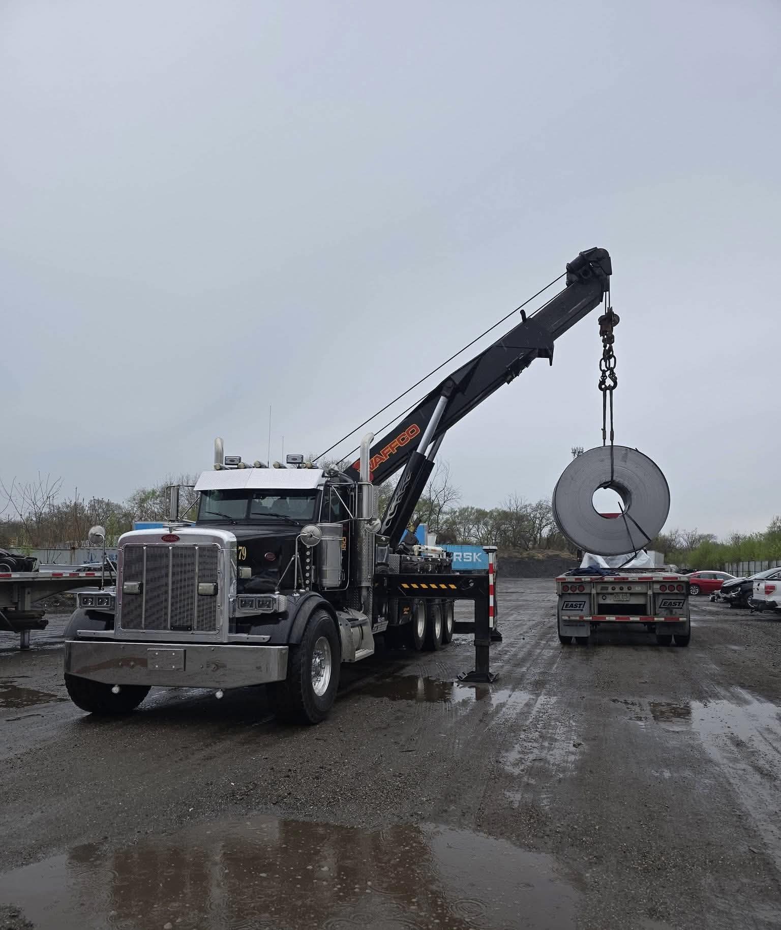 Waffco crane truck lifting a steel coil from a trailer